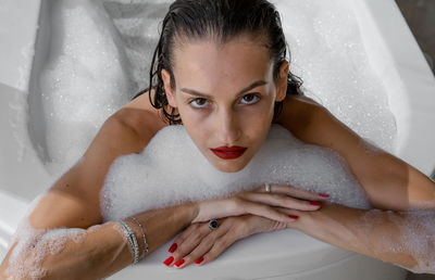 Portrait of woman wearing red lipstick relaxing in bath