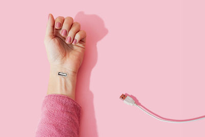 Close-up of woman hand against pink background