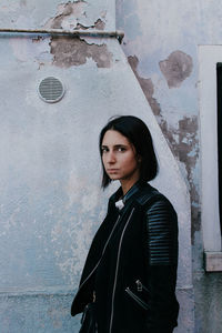 Portrait of beautiful young woman standing against wall