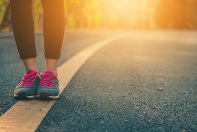 Low section of woman wearing sports shoes while standing on road