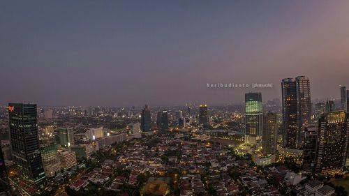 Aerial view of illuminated buildings in city against sky