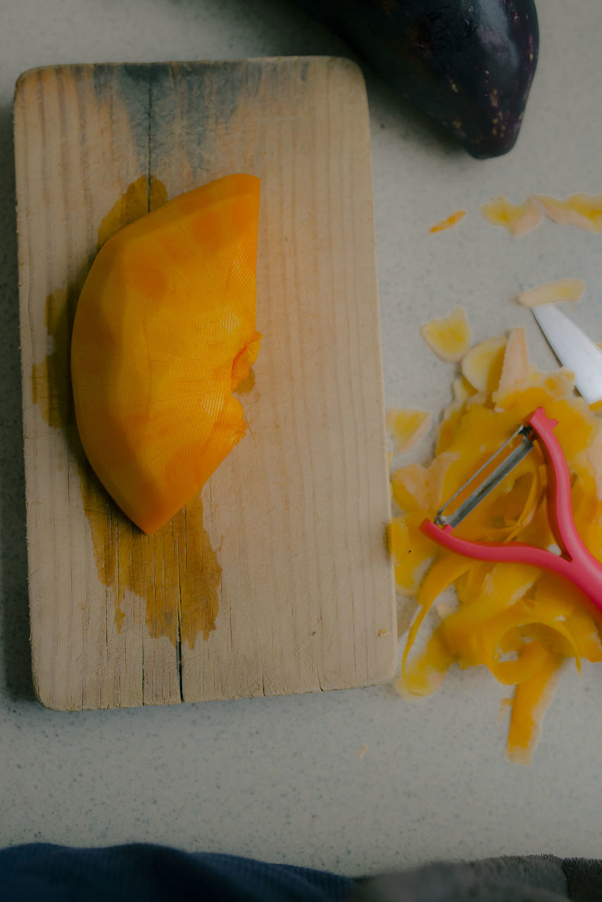 HIGH ANGLE VIEW OF YELLOW AND CUTTING BOARD ON TABLE