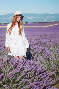 Young long hair woman in hat and dress among lavender fields in provence, france.