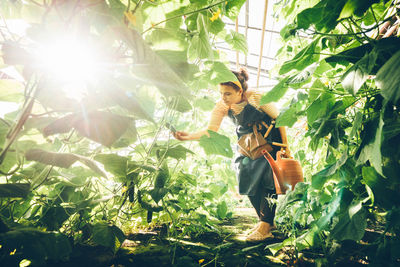 Portrait of young woman standing amidst plants