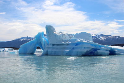 Scenic view of glaciers in lake against blue sky