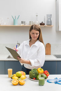 Portrait of smiling young woman using digital tablet while sitting on table