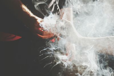 Cropped image of people holding burning cigarette