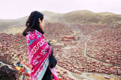 Young woman overlooking townscape against mountains