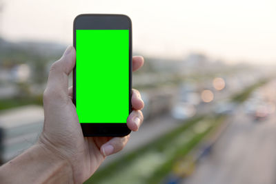 Cropped hand of man photographing traffic from smart phone