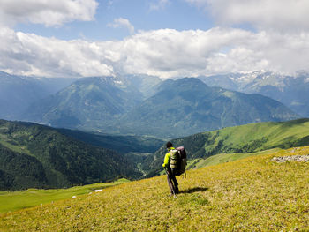 Rear view of man standing on mountain against sky