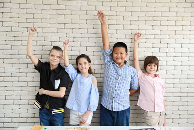 Portrait of happy friends standing against wall