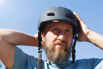 Portrait of man with arms raised against blue sky