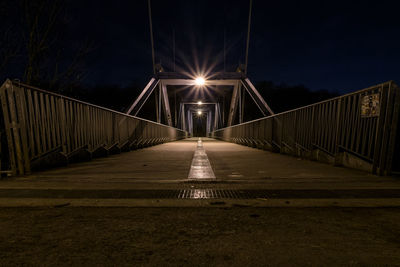 Illuminated footbridge against sky at night