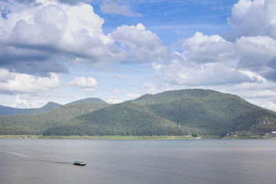 Scenic view of sea by mountains against sky