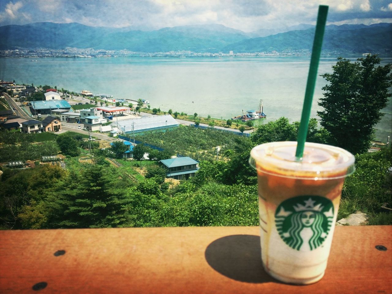 drink, refreshment, table, food and drink, water, sky, tree, mountain, green color, sea, nature, tranquility, growth, freshness, cloud - sky, beauty in nature, outdoors, cloud, day, plant