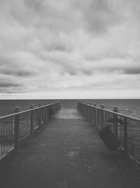 Pier on sea against cloudy sky