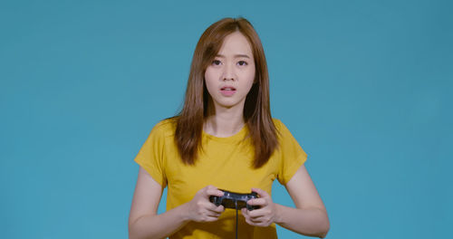 Portrait of teenage girl standing against blue background