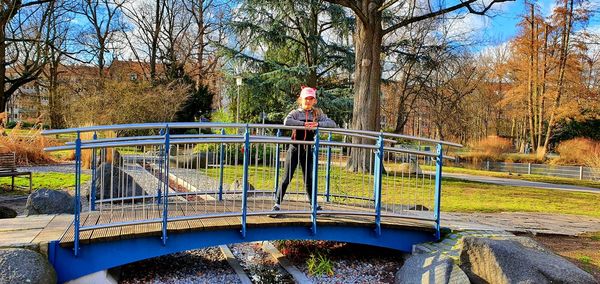 Rear view of man on footbridge against trees