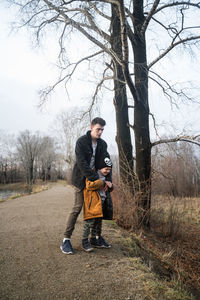 Full length of young man with boy standing in forest