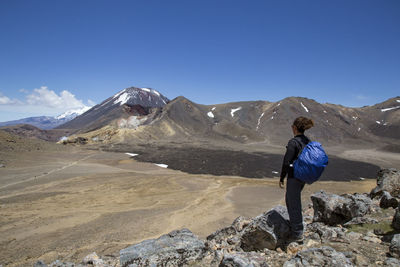 Rear view of man on rock against sky