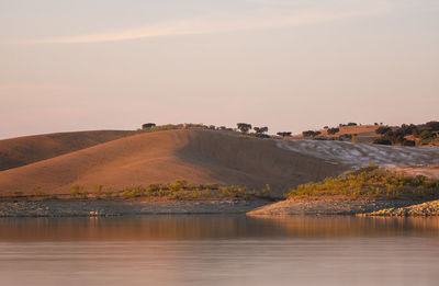 Desert like hill landscape with reflection on the water on a dam lake reservoir in terena, portugal