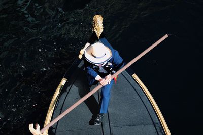 High angle view of man holding oar on boat in river
