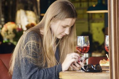 Woman using smart phone while sitting at table