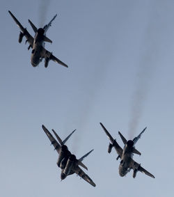 Low angle view of helicopters flying against sky