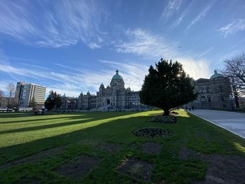 Lawn in front of buildings against sky