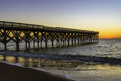 Pier over sea against clear sky during sunset