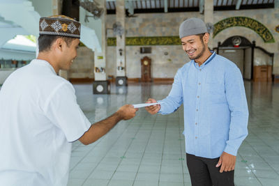 Smiling man receiving envelope in mosque