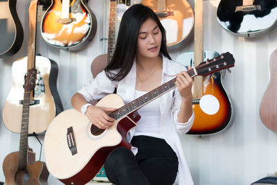 Young woman playing guitar in store