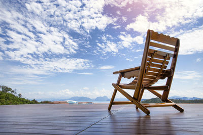 Empty chair on shore against sky