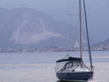 Sailboat in sea against mountain