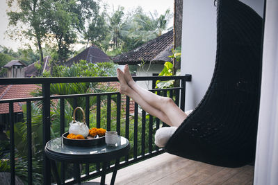 Low section of woman relaxing on swing at balcony
