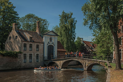 Bridge over river by buildings against sky