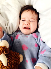 High angle view of cute baby crying while lying on bed