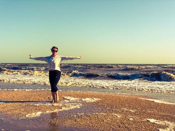 Full length of man standing on beach against clear sky