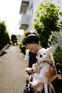 Mid adult woman carrying sleeping chihuahua while standing on street