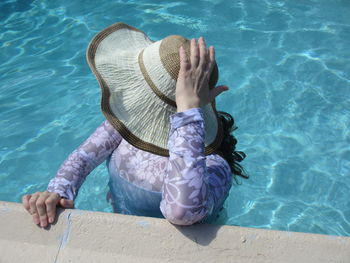 High angle view of woman wearing hat standing in swimming pool