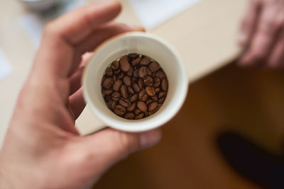 Close-up of hand holding cup of coffee beans