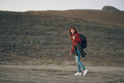Full length portrait of smiling young woman on land