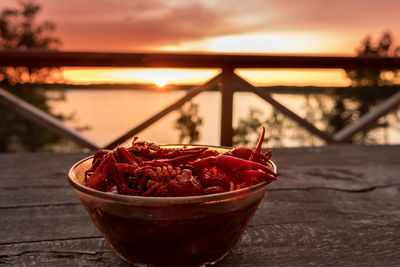 Close-up of red water on wood against sky during sunset