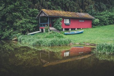 Built structure by lake against trees and plants