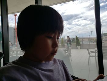 Close-up portrait of boy looking through window