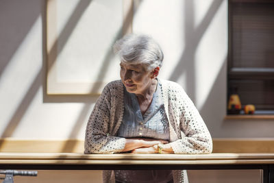 Lonely senior woman leaning on railing, looking down