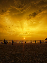 Silhouette people on beach against sky during sunset