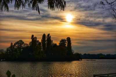 Silhouette trees by lake against sky during sunset