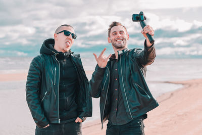 Young man photographing while standing on beach