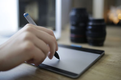 Midsection of man using smart phone on table